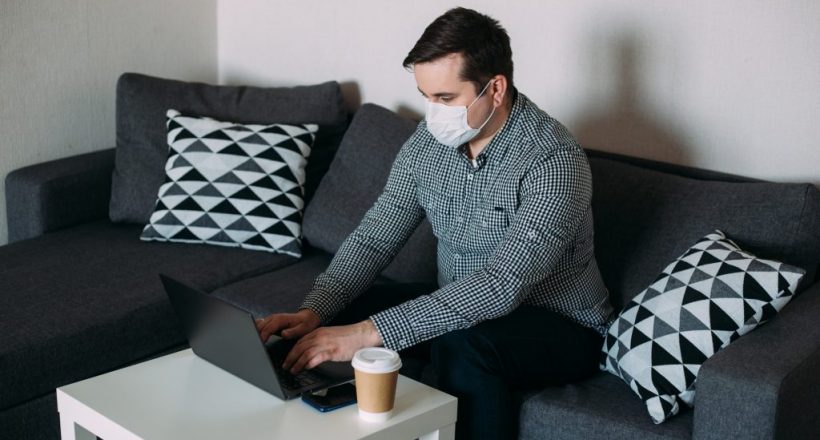 man working on laptop wearing mask from home office